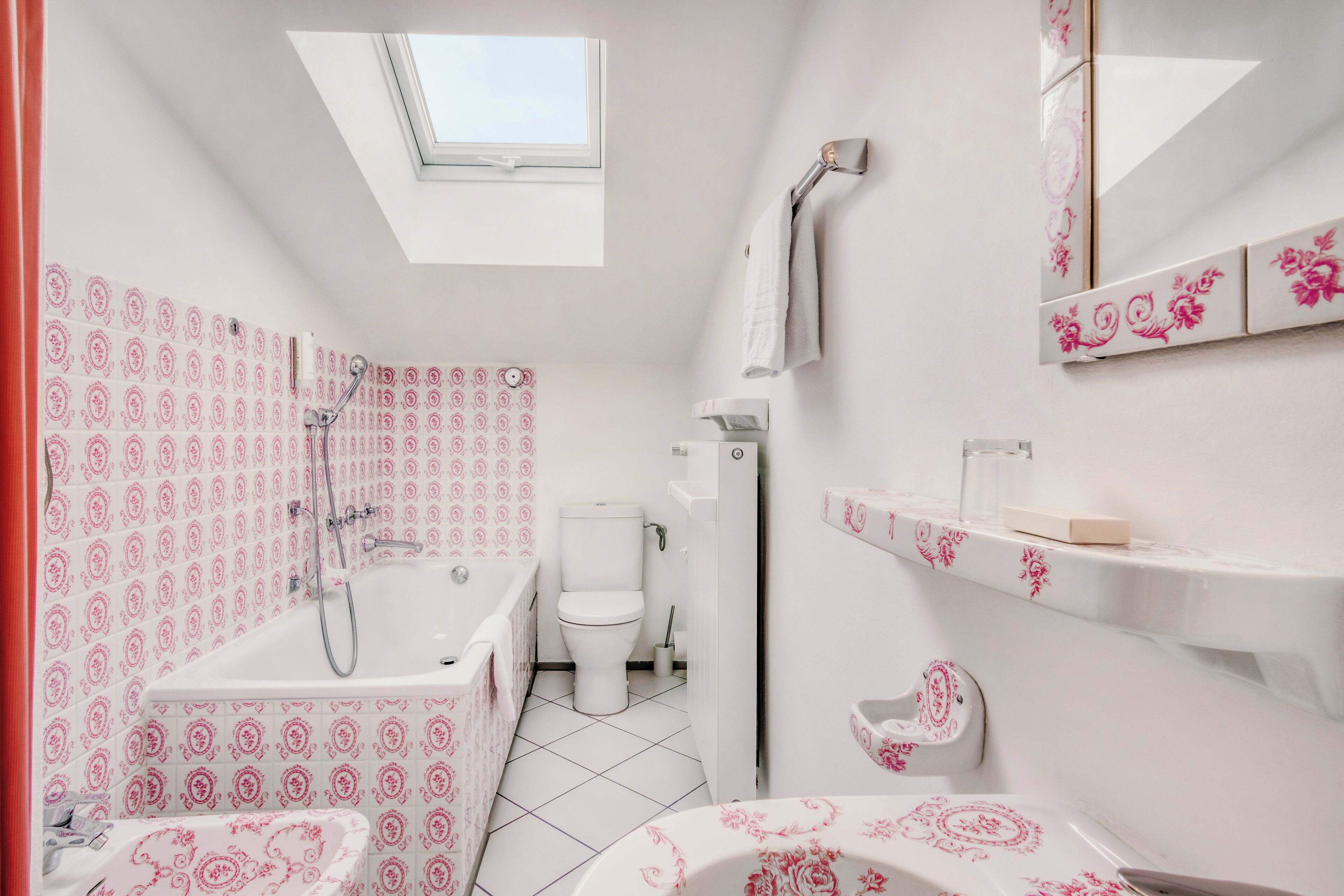 A bathroom with a skylight, a bathtub, a toilet, and a shower.
