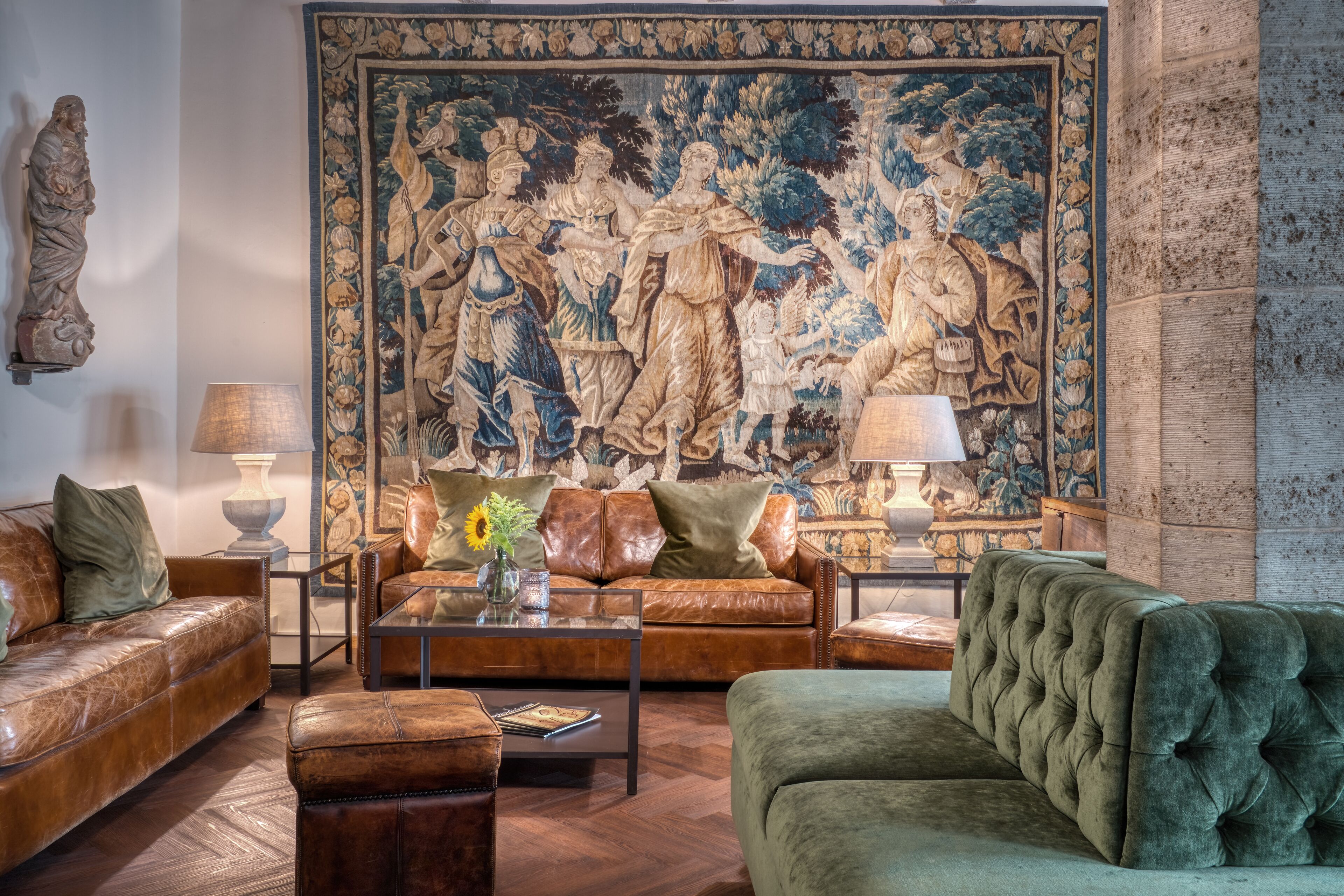 Ein Wohnzimmer mit einem großen Wandteppich, Ledersofas, einem Couchtisch und einer Lampe.