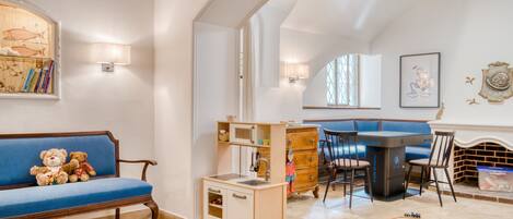 A cozy living room with a blue sofa, a small kitchen area, and a fireplace.