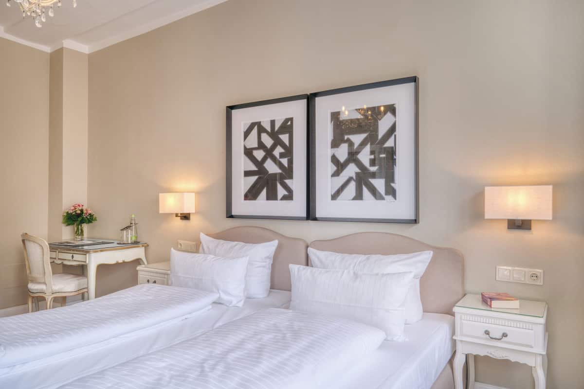 A hotel room with two beds, a desk, and a chair.