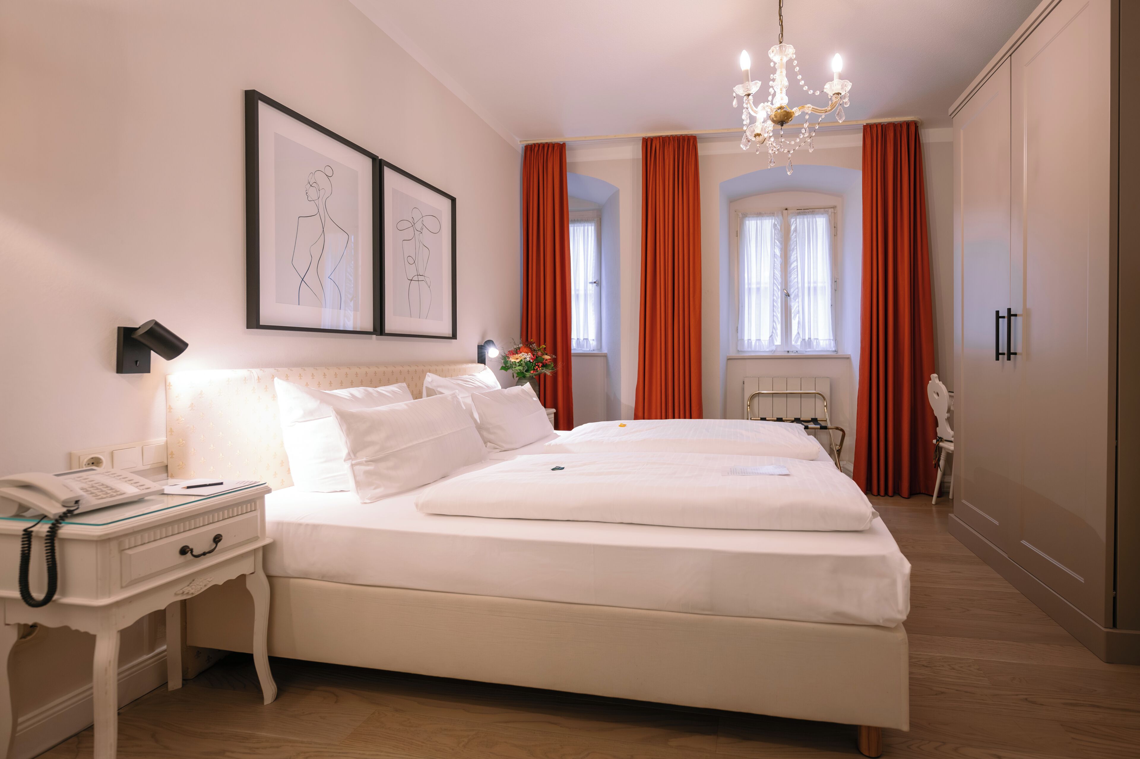 Un dormitorio ordenado con una cama grande, una mesita de noche con un teléfono y un cuadro en la pared.