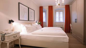 Ein ordentlich eingerichtetes Schlafzimmer mit einem großen Bett, einem Nachttisch mit Telefon und einem gerahmten Bild an der Wand.