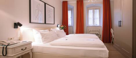 Un dormitorio ordenado con una cama grande, una mesita de noche con un teléfono y un cuadro en la pared.