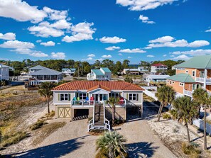 Une maison située en bord de mer, avec un toit rouge, plusieurs terrasses et un garage fermé.