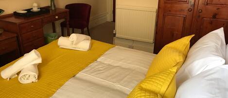 A hotel room with a bed, a desk, a chair, and a dresser.