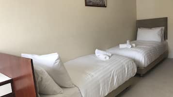 Habitación de hotel con dos camas, cada una con sábanas y almohadas blancas, cabeceros de madera y un cuadro de caballos en la pared.