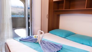 A hotel room with a bed, a view of a mountainous landscape, and a wooden headboard. - Holiday Apartment of Your Dreams a2a (Pag)