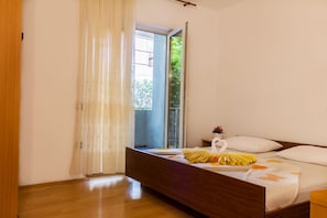 Un dormitorio con una cama de madera, una ventana con vistas a la vegetación y una cortina.