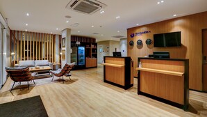 Un hall d’hôtel comprenant un comptoir d’accueil, un espace salon et un réfrigérateur.