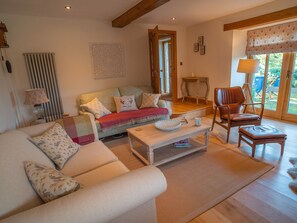 Un salon confortable avec un canapé, un fauteuil et une table basse, un radiateur et une fenêtre donnant sur un beau paysage.