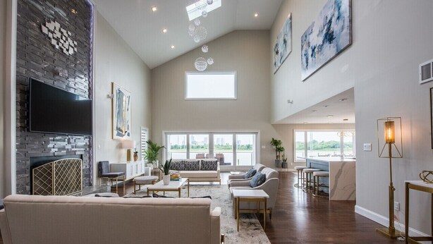 Un salón amplio con chimenea, un televisor grande y un techo alto con tragaluces.