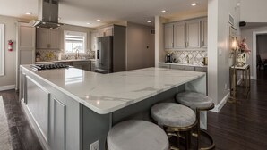 Una cocina amplia con una isla grande, electrodomésticos de acero inoxidable y taburetes de bar.