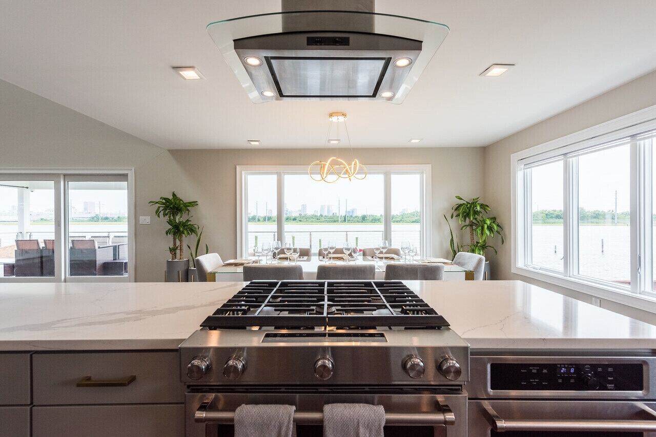 A modern kitchen with a central island, stainless steel appliances, and large windows offering views of the city.