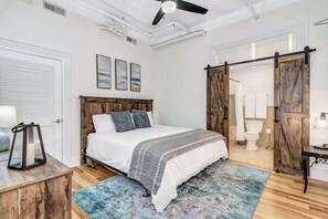 A bedroom with a bed, a wooden headboard, a blue rug, and a wooden chest of drawers. - Downtown Asheville Loft - Steps to Dining & Shops (Asheville)