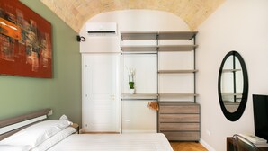 Une chambre à coucher avec un lit, une armoire, un miroir et un plafond en briques.