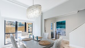 A dining area with a gray table, wicker chairs, and a chandelier. - Golf Cart ~ Lake Views ~ Community Pool ~ Patio (Miramar Beach)