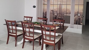 En matplats med utsikt över staden genom stora fönster, ett modernt matbord och trästolar.