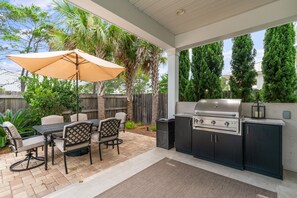 An outdoor kitchen with a grill, dining table, chairs, and an umbrella. - Golf Cart ~ Private Pool ~ Near Beach ~ Grill (Santa Rosa Beach)