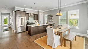 A modern kitchen with a central island, stainless steel appliances, pendant lighting, and a view of the outdoors. - Golf Cart ~ Private Pool ~ Near Beach ~ Grill (Santa Rosa Beach)