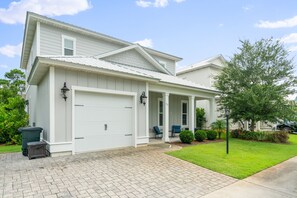 A two-story house with a covered porch, a garage, and a well-maintained lawn. - Golf Cart ~ Private Pool ~ Near Beach ~ Grill (Santa Rosa Beach)