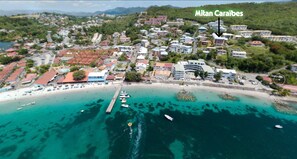 Vue aérienne d’une ville côtière avec un port de plaisance, des bâtiments et une plage.