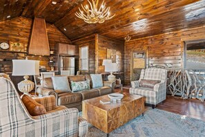 A log cabin interior with a living room, kitchen, and dining area.