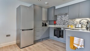 A modern kitchen with grey cabinets, a stainless steel refrigerator, a microwave, and an oven. - Belle House, Apt 2 (Filey)