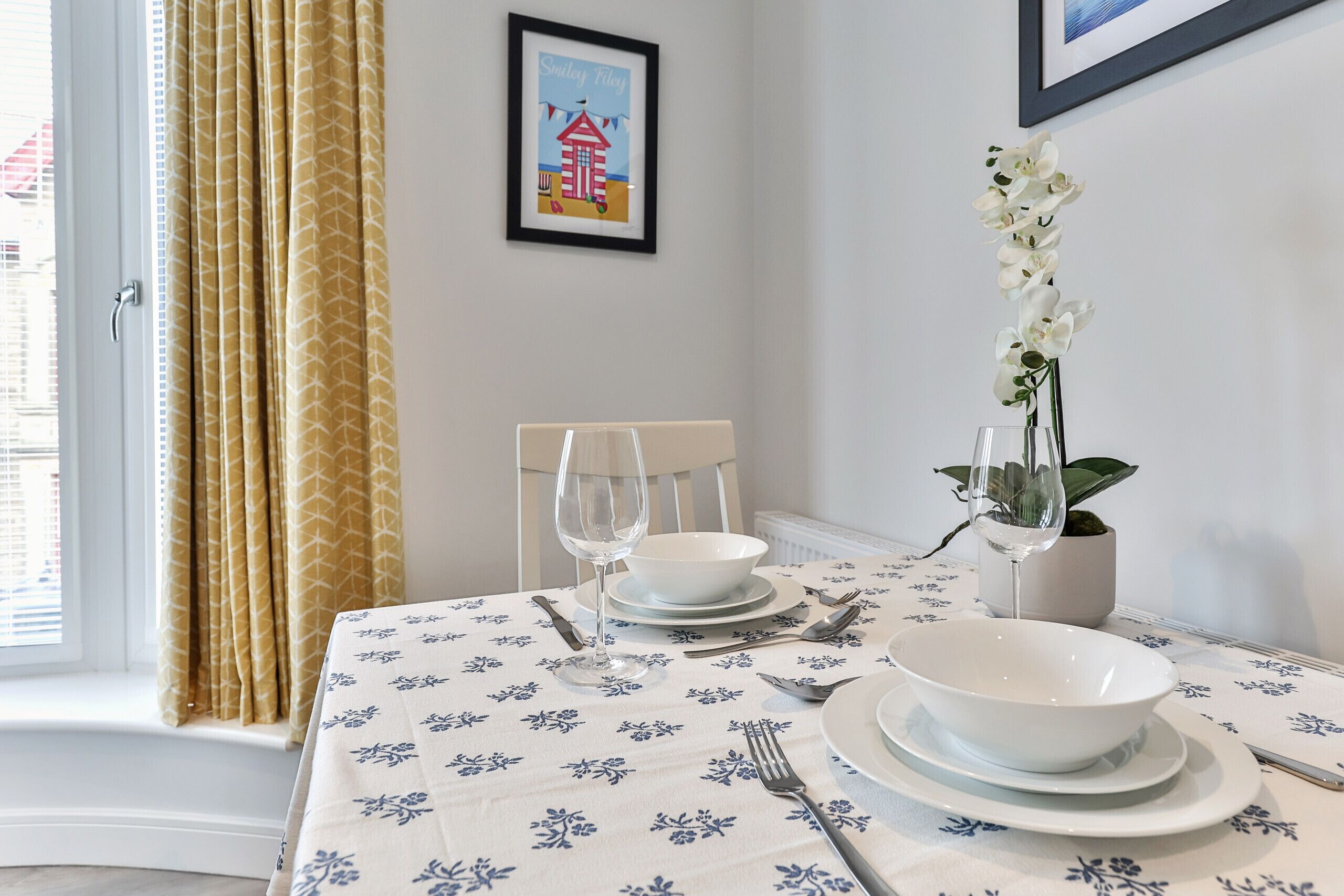 A dining table set with white plates, bowls, and cutlery.