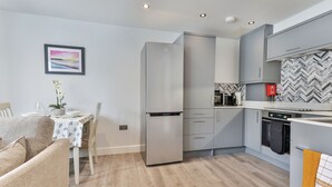 A modern kitchen with grey cabinets, a stainless steel refrigerator, and a herringbone-patterned backsplash. - Belle House, Apt 2 (Filey)