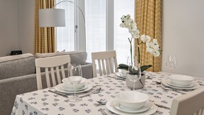 A dining area with a table set for four, including plates, bowls, cutlery, and wine glasses. - Belle House, Apt 3 (Filey)