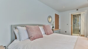 A bedroom with a bed, nightstands, a mirror, a potted plant, and a door leading to a bathroom. - Belle House, Apt 3 (Filey)