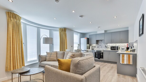 A modern living room with a sofa, a coffee table, and a kitchen in the background. - Belle House, Apt 3 (Filey)