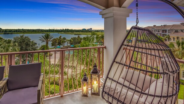 A balcony with a view of a lake, a hanging chair, and two lanterns. - Top floor condo w/view of lake, pool and fireworks! - Next to conv. center (Orlando)