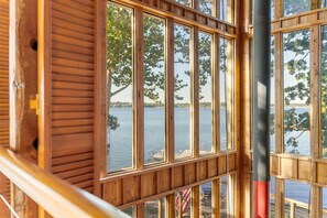 Une cabane en bois dotée de grandes fenêtres donnant sur un lac.