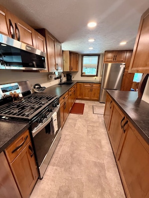 Una cocina moderna con armarios de madera, electrodomésticos de acero inoxidable y un ventanal que proporciona luz natural.