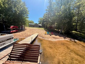 A wooden dock extending into a muddy water body with a boat docked on the left.
