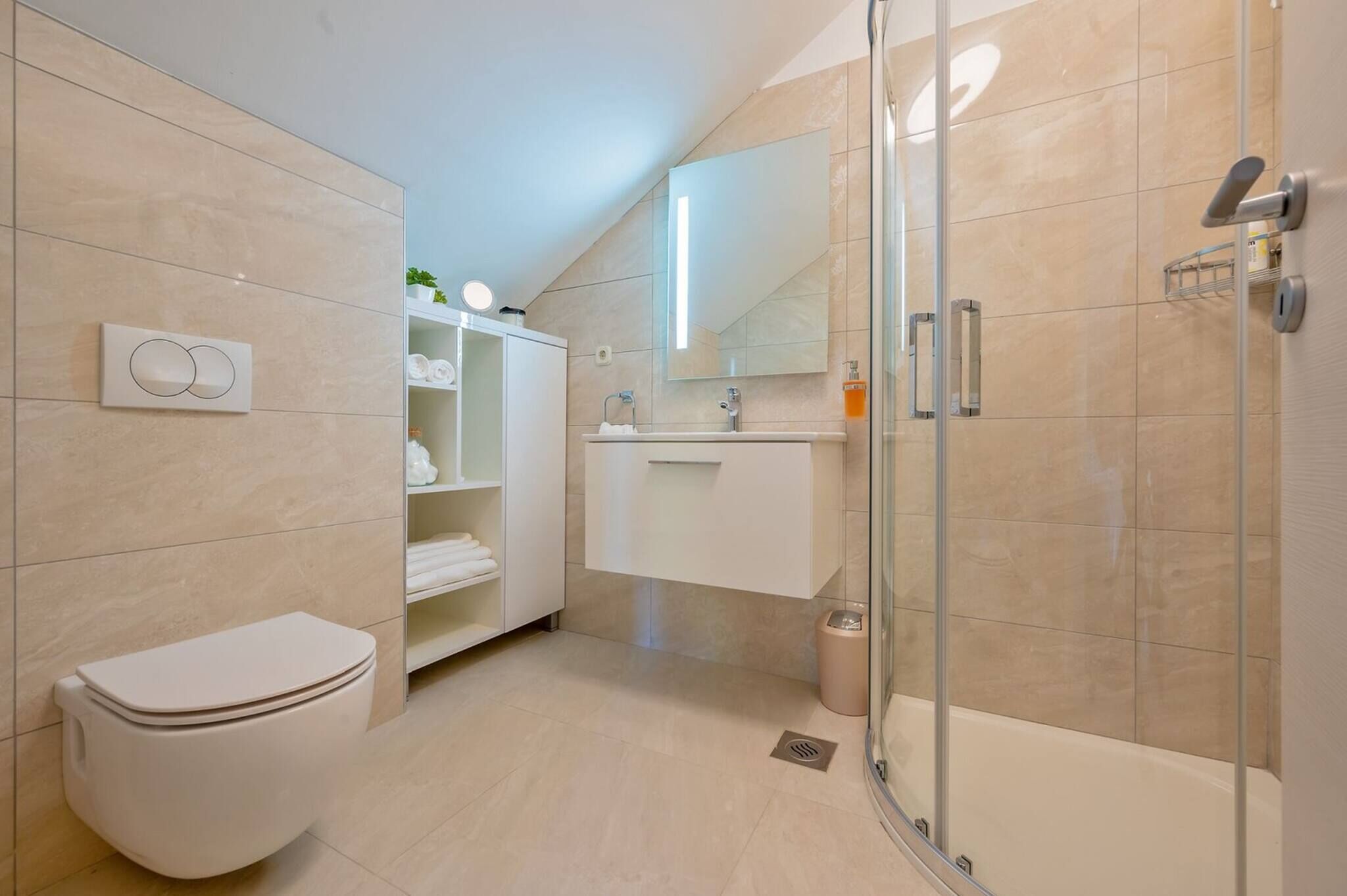 A modern bathroom with a toilet, a glass-enclosed shower, a sink, and a mirror.