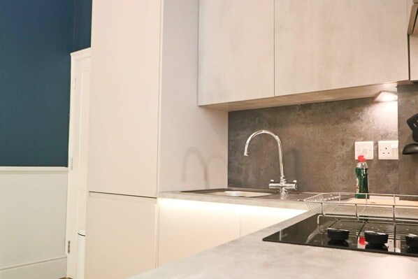 A modern kitchen with a built-in gas stove, a stainless steel sink, and light-colored cabinets. - Alma Studios - Apartment 3 - Hopewell (Bristol)