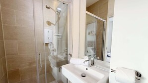 Ein modernes Badezimmer mit einer gläsernen Dusche, einem weißen Waschbecken und einem großen Spiegel.