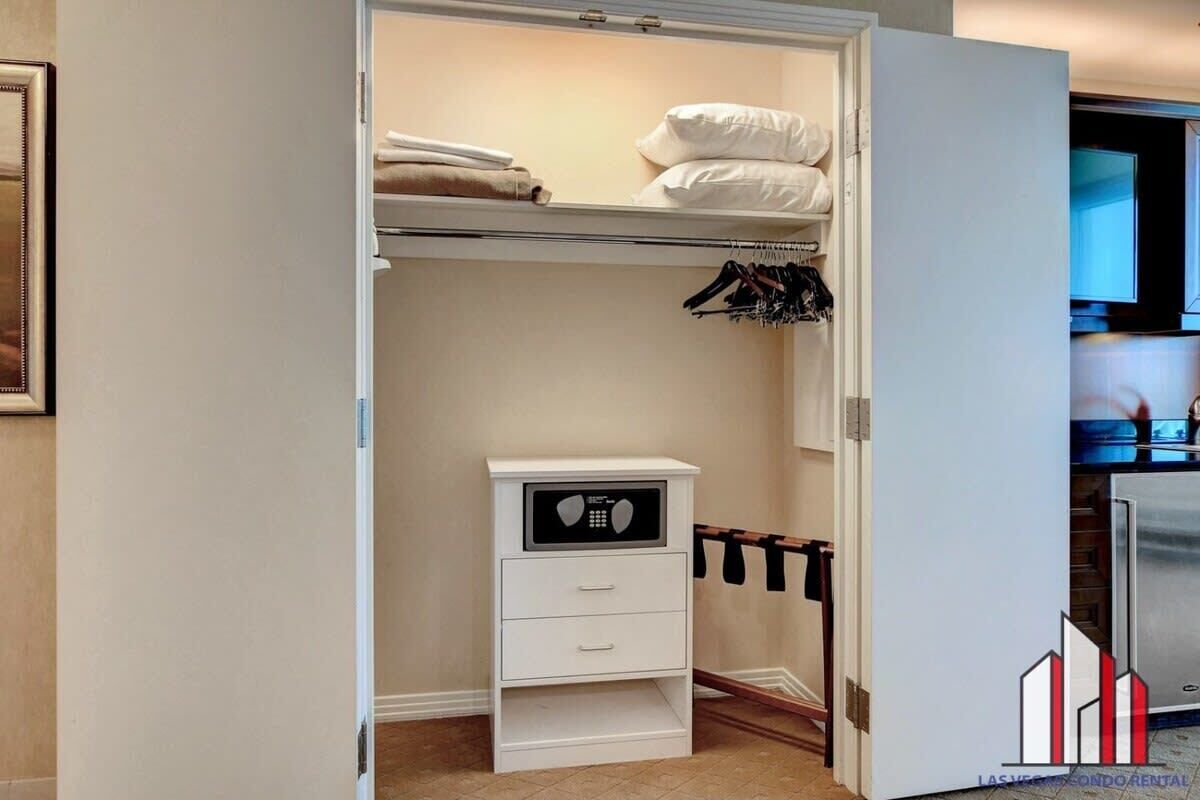 Un vestidor con cama en la parte superior, un pequeño armario blanco y una percha con ropa.
