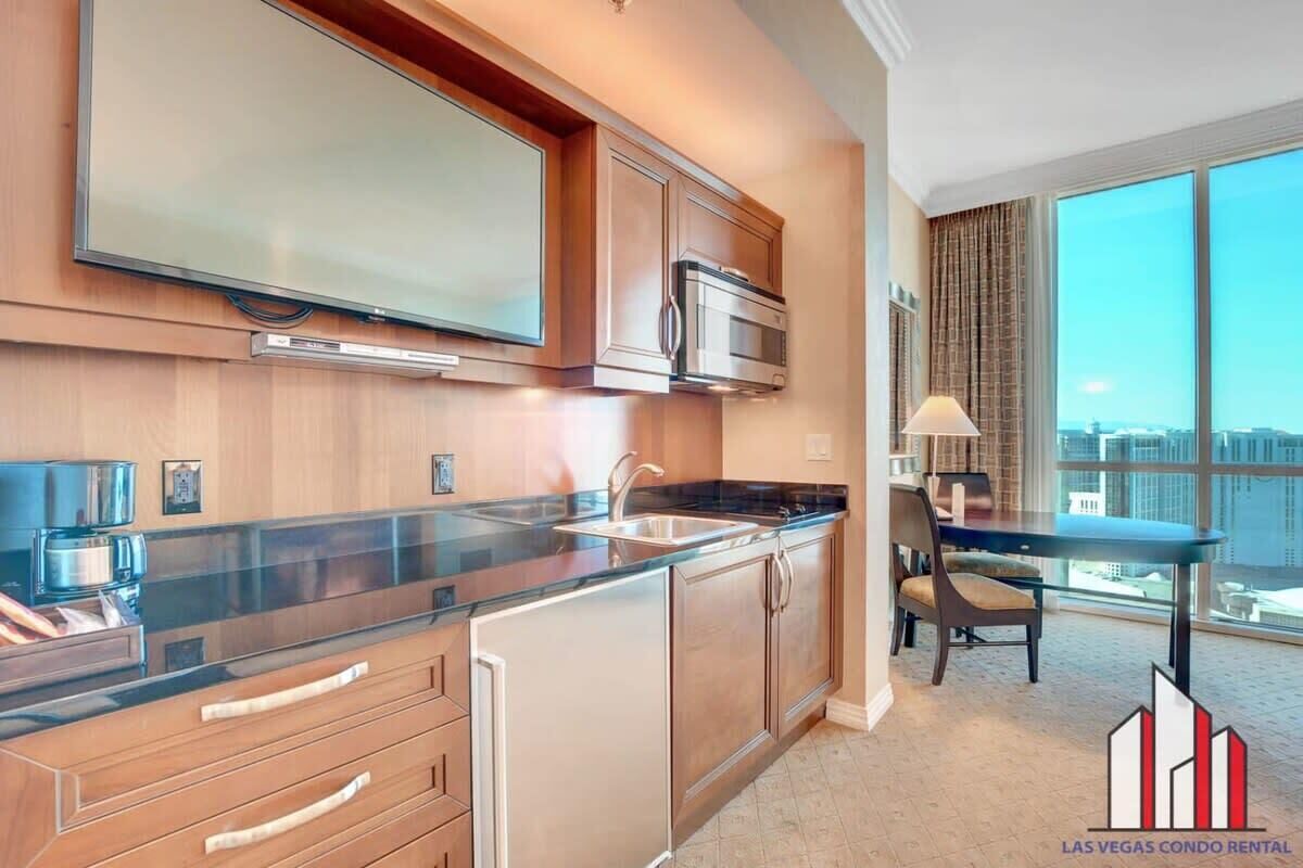 A modern kitchen with stainless steel appliances, a large window, and a dining area with a table and chairs.