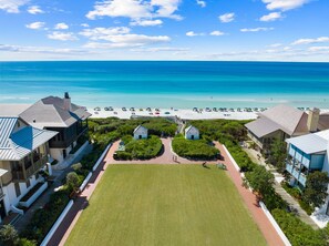 A coastal property with a large lawn, beach access, and a view of the ocean.