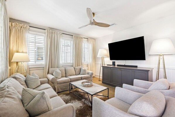 A living room with a sofa set, a coffee table, a TV, and a ceiling fan.