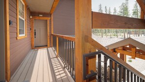 Terraza de madera con una puerta y un buzón, que conduce a un porche cubierto.