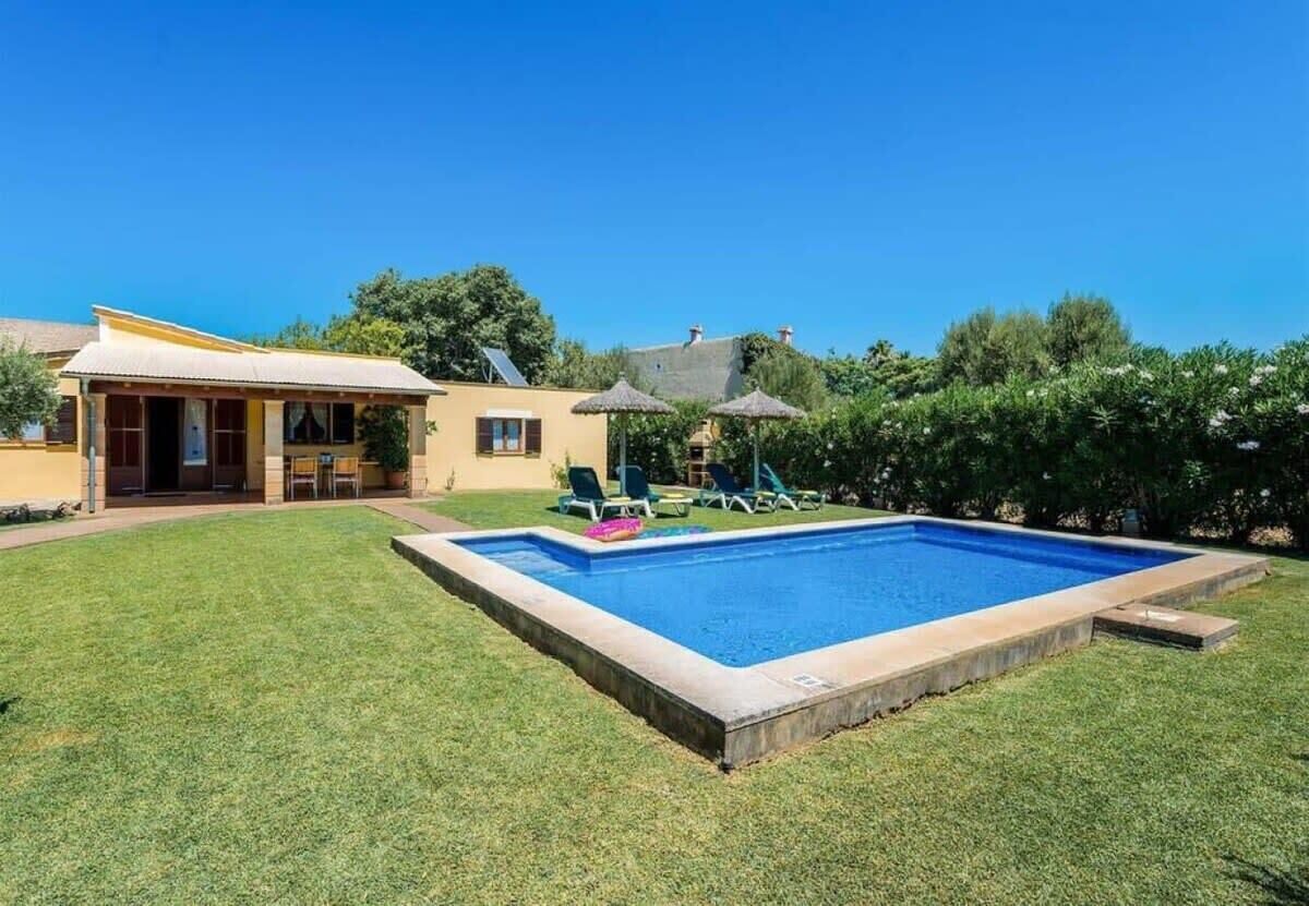 Un patio trasero con piscina, un porche cubierto y una casa.