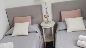 Ein Hotelzimmer mit zwei Betten, einem kleinen runden Tisch mit einer Lampe und Handtüchern auf den Betten.