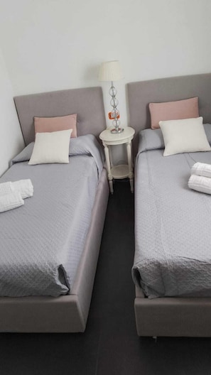Une chambre d’hôtel avec deux lits, une petite table ronde avec une lampe et des serviettes sur les lits.