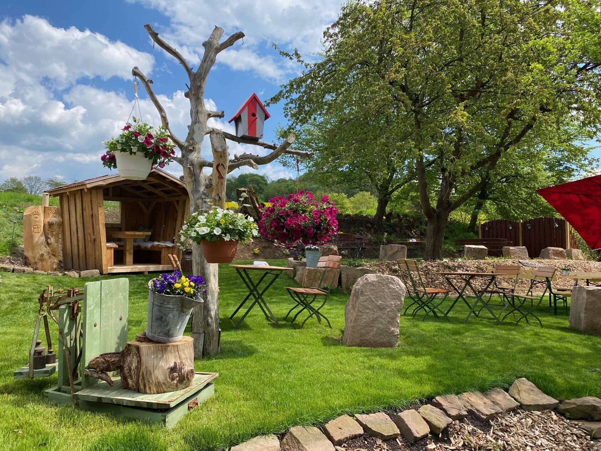 A rustic outdoor setting with a wooden structure, a birdhouse, and a stone bench.