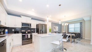 A modern kitchen with white cabinets, stainless steel appliances, and a central island with bar stools. - BE307  Storey Lake Condo 2 bed 2 bath  Free Waterpark (Kissimmee)