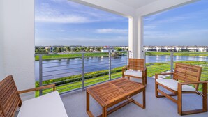 A balcony with wooden furniture and a view of a river and buildings. - BE307  Storey Lake Condo 2 bed 2 bath  Free Waterpark (Kissimmee)